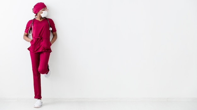long view of woman medic leaning on white wall