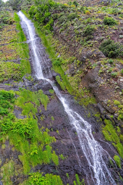 Photo long waterfall along the paved road and tunnel in the parish of so vicente on madeira island