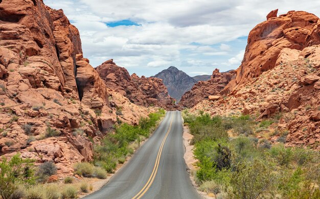 Photo long winding highway with ups and downs cloudy blue sky valley of fire nevada usa