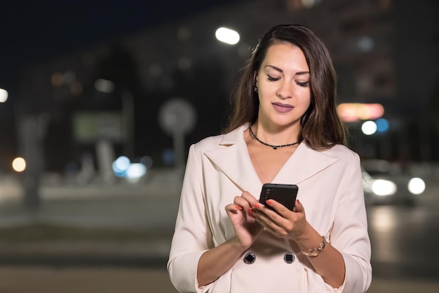 La donna di affari dai capelli lunghi digita i messaggi sullo smartphone