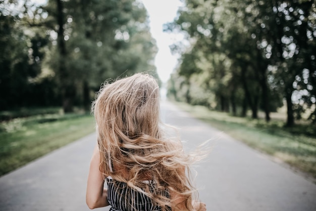 longhaired girl rear view runs along a forest road runs away from fears to meet a brighter future