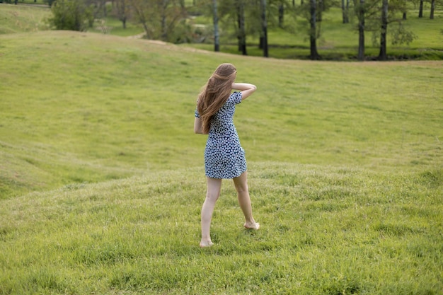 Longhaired girl in the summer in a dress from the back