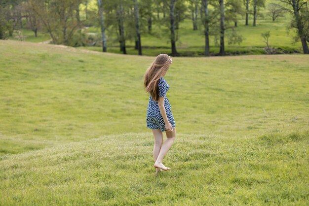 Longhaired girl in the summer in a dress from the back