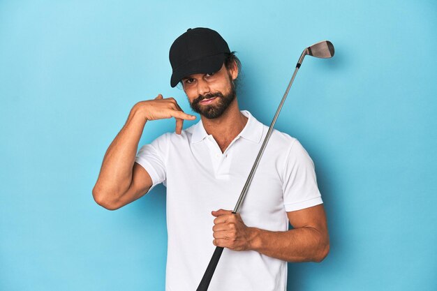 Длинноволосый игрок в гольф с клубом и шляпой, показывающий жест мобильного звонка пальцами