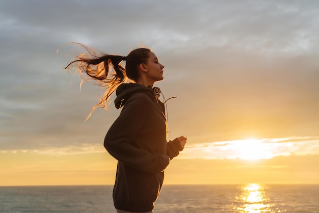 Longhaired young girl runs on the sea promenade at sunset leads an active healthy lifestyle