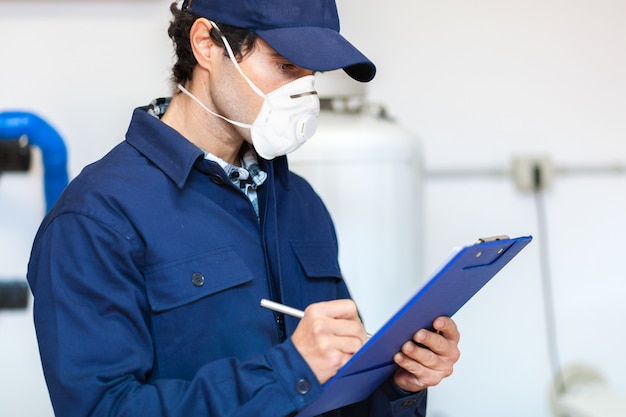 Loodgieter aan het werk dat een masker, coronavirusconcept draagt