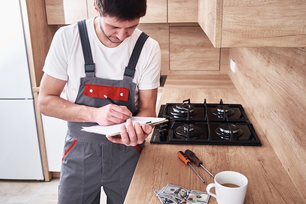 Loodgieter in uniform tekent een contract voor diensten in de keuken