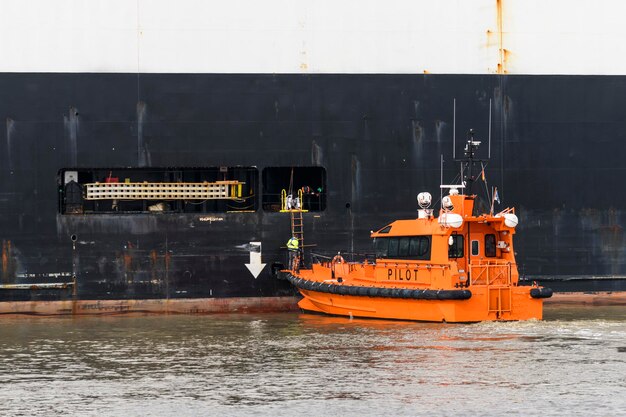 Loodsboot en vrachtschip op zee Loodsinscheping Loodswezen