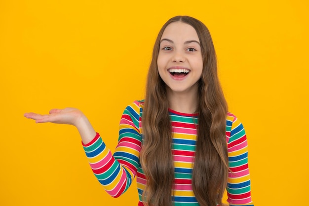 Look at advert Teenager child points aside shows blank copy space for text promo idea presentation poses against yellow background