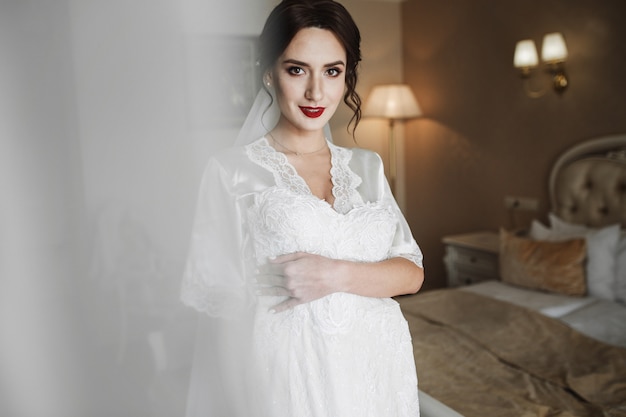 Look from behind the curtain at seductive bride standing with wedding dress