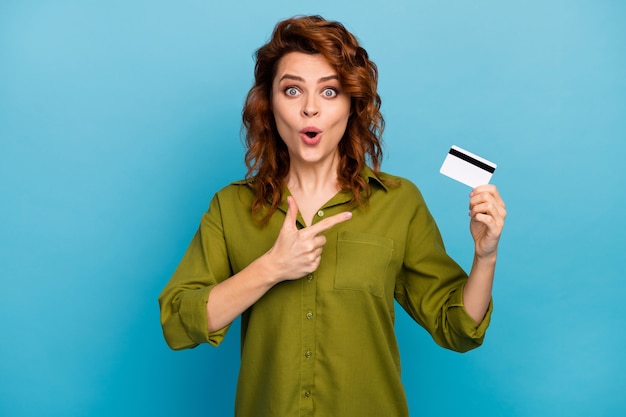 Посмотрите на его невероятную удивленную женщину, держащую кредитную карту указательным пальцем, впечатленную легко оплачиваемыми банковскими услугами, стильная одежда в стиле одежды, выделенная на синем цветном фоне