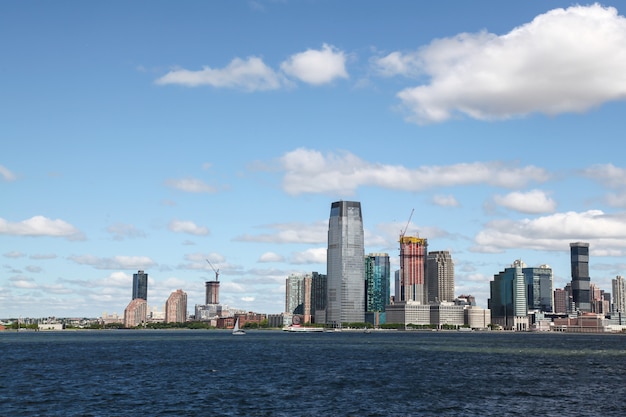 Look on the sailboat cruising in New York harbor buildings of Manhattan island in the background