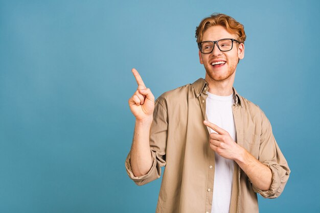 look over there! happy young handsome man in casual pointing away and smiling while standing