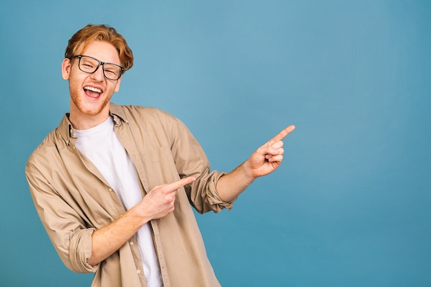 look over there! happy young handsome man in casual pointing away and smiling while standing