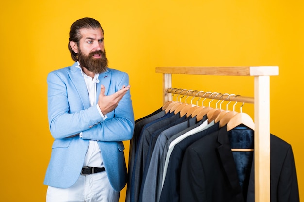 Look over there man go shopping in clothing store our studio atelier presents any fashion style Large selection of mens suits bearded man choose jacket on hanger male wardrobe concept