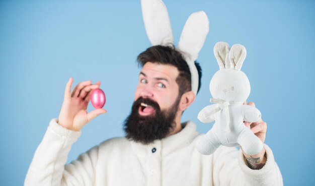 Look what i found Hipster cute bunny blue background Easter bunny My precious Funny bunny with beard and mustache hold pink egg Easter symbol concept Bearded man wear bunny ears Egg hunt