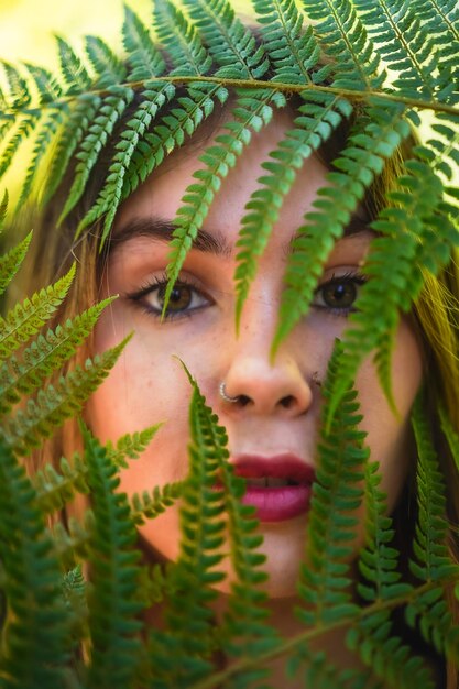 Foto sguardo di una giovane donna bruna in natura in un parco naturale tra foglie di felce