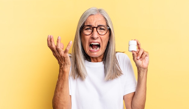 Looking angry, annoyed and frustrated screaming wtf or whatãâ¢ãâãâs wrong with you and holding a pills bottle