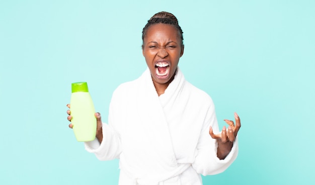 Looking angry, annoyed and frustrated wearing bath robe and holding a shampoo