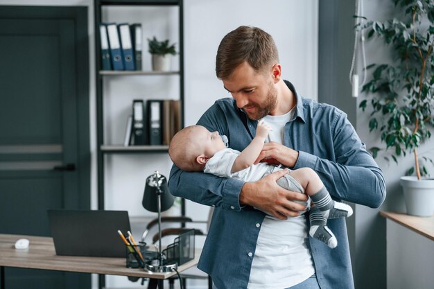 Looking at the baby father with toddler is indoors in the office