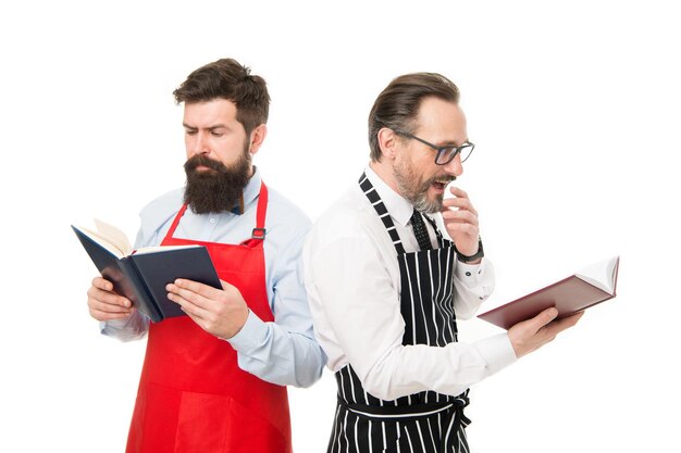 Looking for better recipe. Improve cooking skill. Book recipes. According to recipe. Men bearded chefs with books or notepads. Culinary concept. Amateur cooks read book recipes. Try something new.