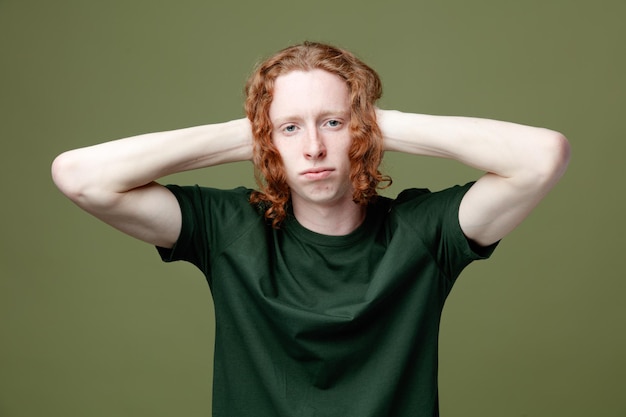 Looking at camera grabbed head young handsome guy wearing green t shirt isolated on green background