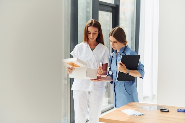 Looking at documents Two doctors in uniform standing indoors and working together