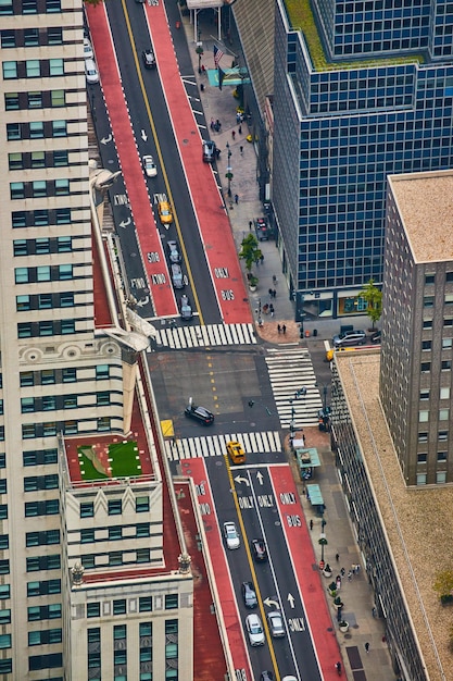 Photo looking down on new york city intersection with red and black lanes and lined with skyscrapers