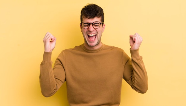 Looking extremely happy and surprised celebrating success shouting and jumping