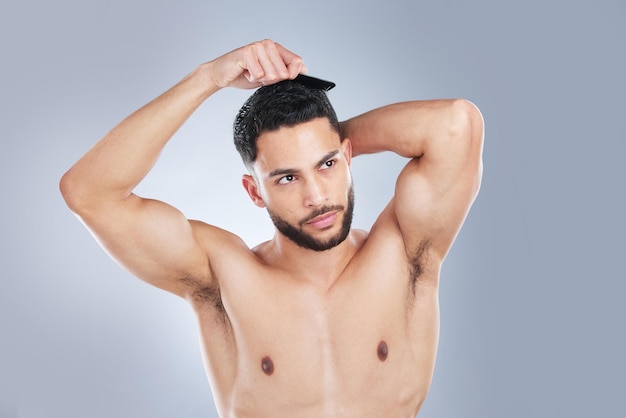 Looking good takes attention to detail Studio shot of a handsome young man combing his hair against a grey background