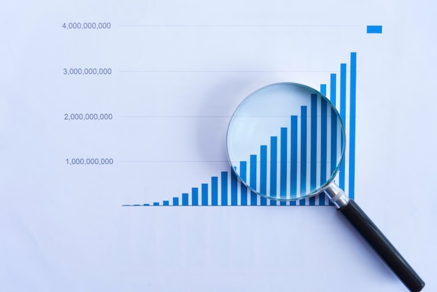 Looking at growth chart with magnifying glass. Graphs, charts and magnifying glass.