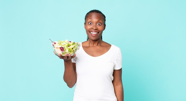 Looking happy and pleasantly surprised and holding a salad