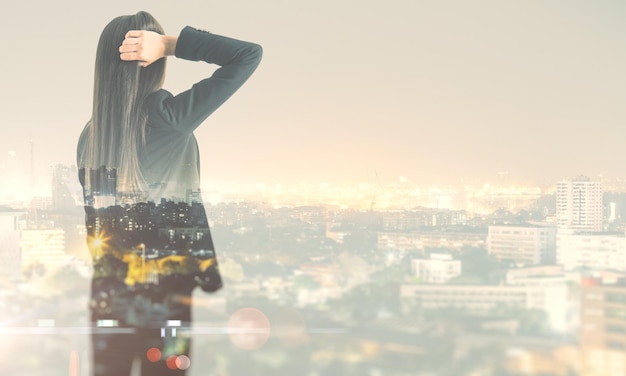 Looking into the future concept with businesswoman looking into the distance and smoky city on background Double exposure