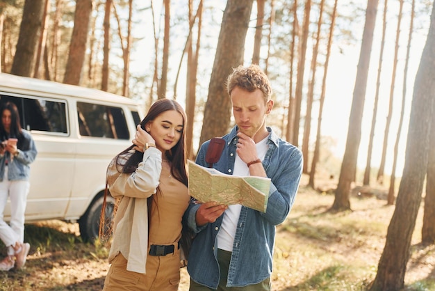 Looking for location by using map Group of young people is traveling together in the forest at daytime