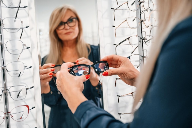 Looking at the mirror Woman in store trying new glasses