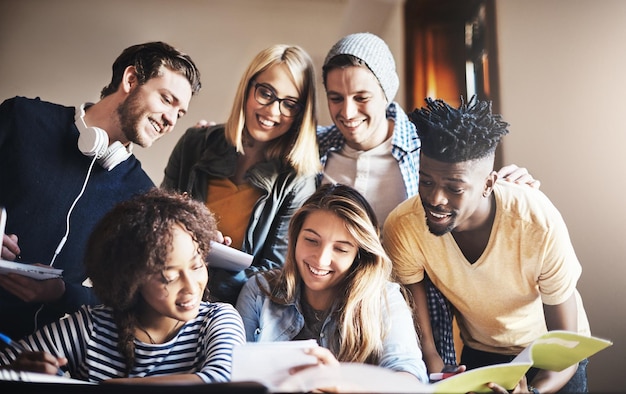 Guardando insieme il nuovo compito ritagliata di un gruppo di studenti universitari che lavorano insieme a un compito in classe