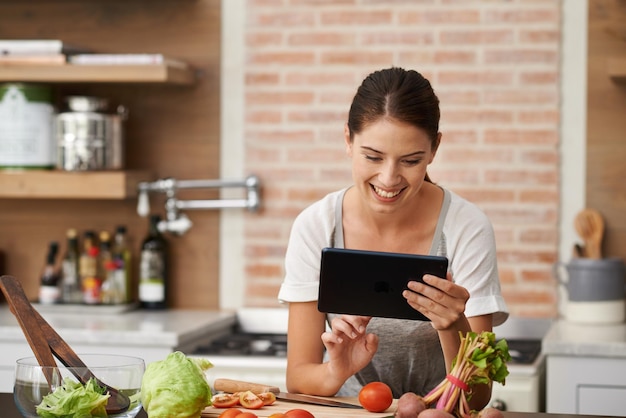 Looking for the perfect recipe online Shot of an attractive young woman using her tablet in the kitchen