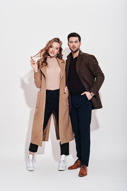 Looking perfect together attractive and welldressed couple posing in studio isolated over grey