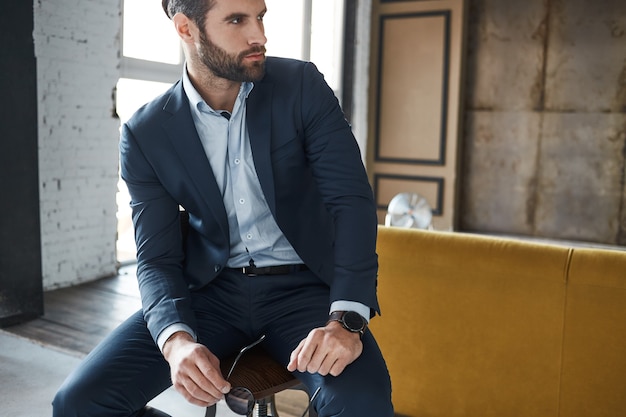 Looking perfectattractive bearded businessman dressed in fashionable suit is thinking about business