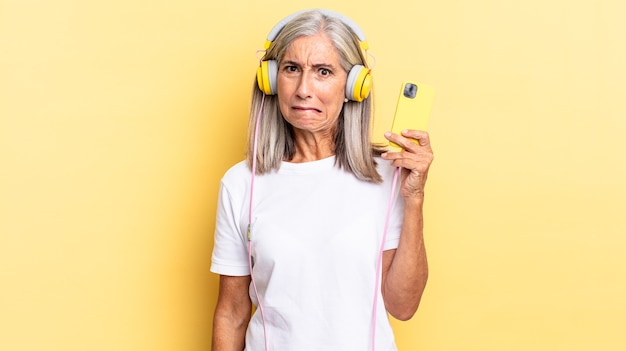 Looking puzzled and confused, biting lip with a nervous gesture, not knowing the answer to the problem with headphones