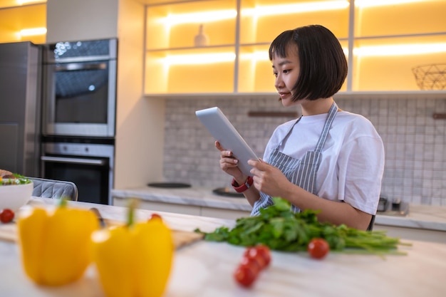 Foto alla ricerca di ricetta. una ragazza in cucina legge un blog di cucina online