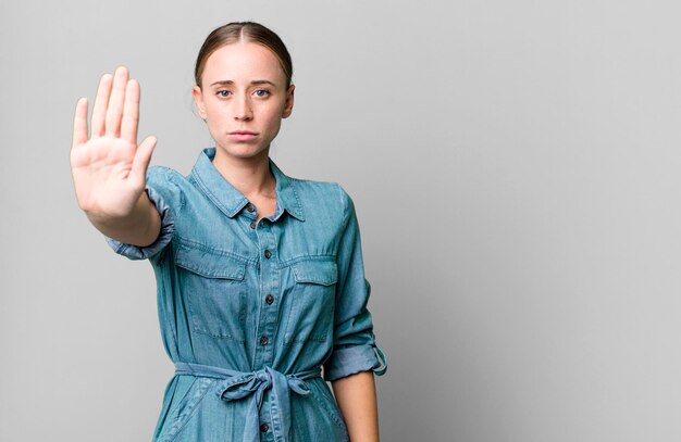 Looking serious showing open palm making stop gesture