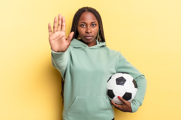 Looking serious, stern, displeased and angry showing open palm\
making stop gesture. soccer concept