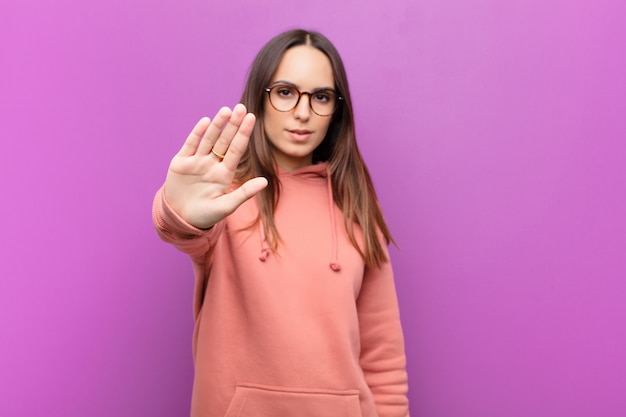 looking serious, stern, displeased and angry showing open palm making stop gesture