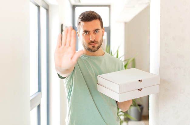 looking serious, stern, displeased and angry showing open palm making stop gesture