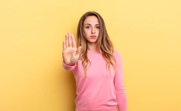 Looking serious stern displeased and angry showing open palm making stop gesture