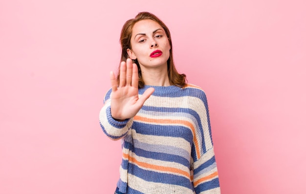 Looking serious stern displeased and angry showing open palm making stop gesture