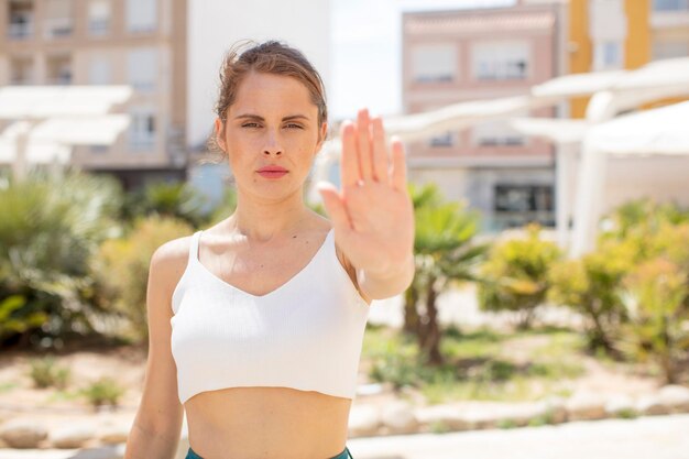 Photo looking serious stern displeased and angry showing open palm making stop gesture