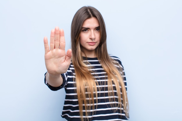 looking serious, stern, displeased and angry showing open palm making stop gesture