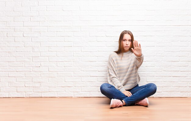 looking serious, stern, displeased and angry showing open palm making stop gesture